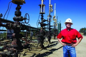 Jim Bray, Pacific Coast Energy public affairs manager, next to cyclic steam injection wells.